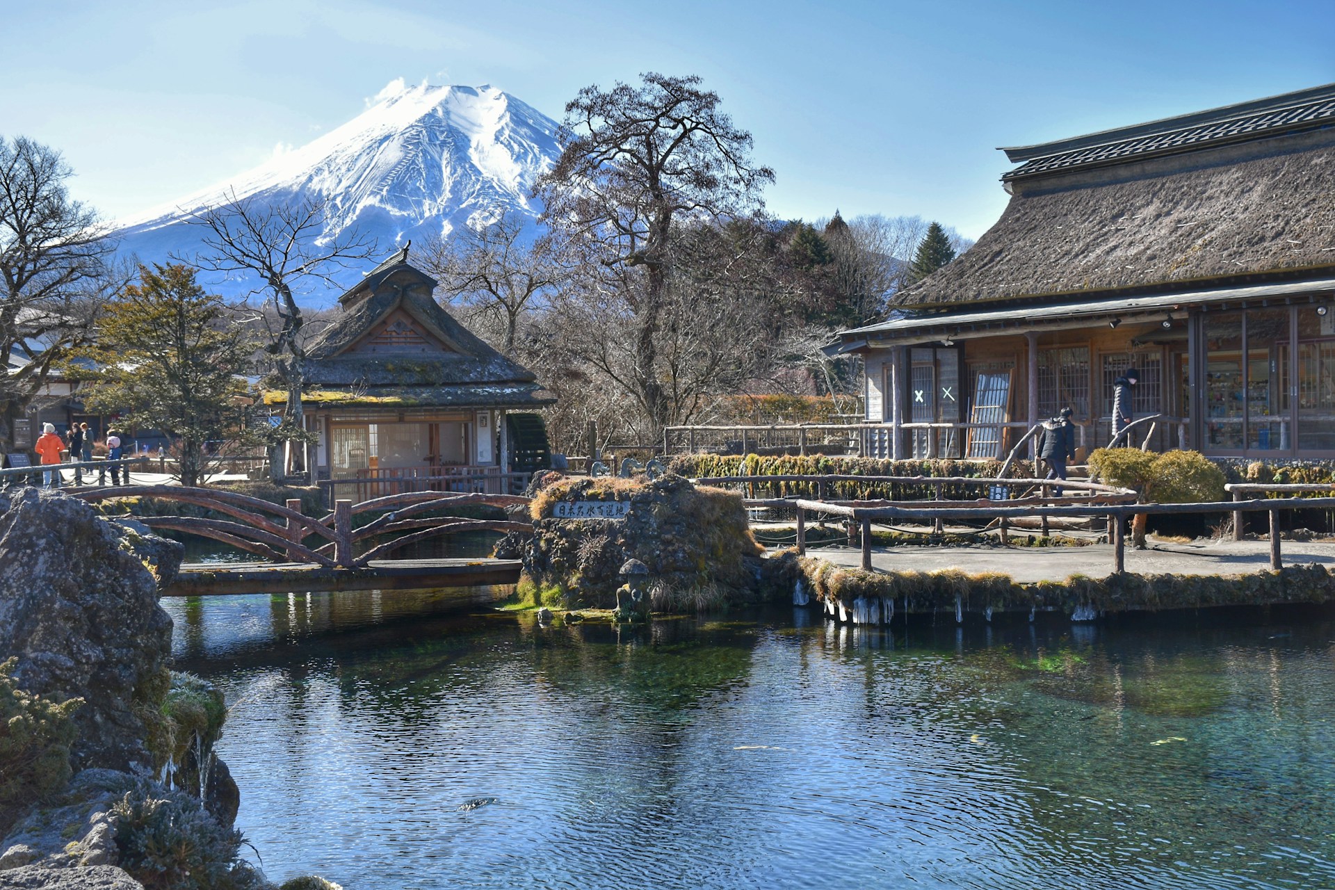 Mt. Fuji behind a traditional Japanese village with a koi pond